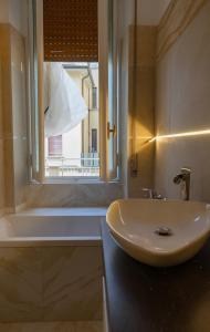 bagno con lavandino, finestra e vasca di PALAZZO NOVECENTO Rooms a Lecco