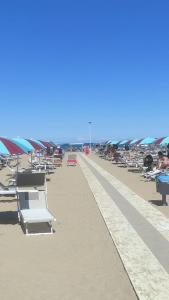 a beach with chaise lounges and umbrellas at Appartamento Orchidea in Rimini