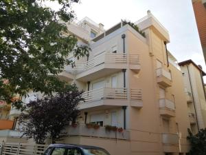 um edifício com varandas e um carro estacionado em frente em Appartamento Orchidea em Rimini