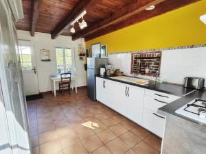 eine Küche mit weißen Schränken und einem schwarzen Kühlschrank in der Unterkunft La Tiote Maison in Fiennes