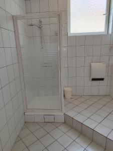 a white tiled bathroom with a shower and a toilet at Esma in Vogošća