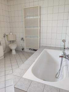 bagno bianco con vasca e servizi igienici di Esma a Vogošća