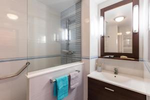 La salle de bains blanche est pourvue d'un lavabo et d'un miroir. dans l'établissement Jardin de la cote d'azur, à Saint-Mandrier-sur-Mer