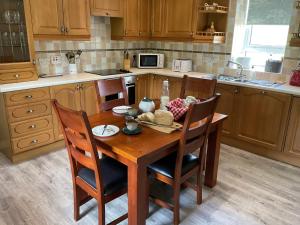 a kitchen with a wooden table with chairs and a kitchen at 6 Calbost in Calbost