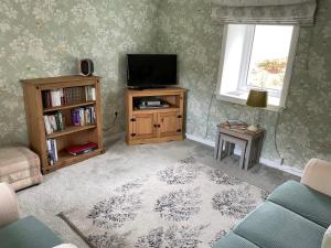 a living room with a television and a book shelf at 6 Calbost in Calbost