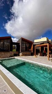 uma casa com piscina em frente a uma casa em CHALE VILAALICE em Monte das Gameleiras