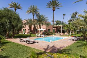 - une piscine avec des chaises longues et des palmiers dans l'établissement Domaine Abiad, à Marrakech