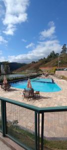 een zwembad met twee banken naast een hek bij Apto Cenário de Montanha in Petrópolis