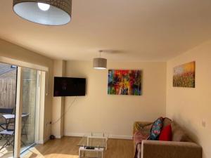 a living room with a couch and a flat screen tv at Contemporary & Cosy Trumpington House, 5 mins to Bio Medical Campus, Addenbrooke's & Papworth hospitals in Cambridge