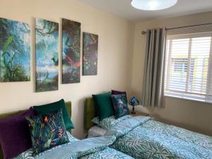 a bedroom with two beds and paintings on the wall at Contemporary & Cosy Trumpington House, 5 mins to Bio Medical Campus, Addenbrooke's & Papworth hospitals in Cambridge