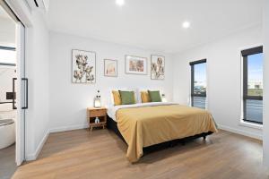 a white bedroom with a bed and two windows at City Edge Apartment 1 (Wheelchair Accessible) in Mount Gambier