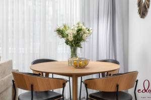 a dining room table with a vase of flowers on it at דירה מדהימה 100 מטר מהים עם חניה פרטית - By Edomlux in Eilat