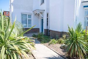 a white house with a blue door and some plants at Fantastic sea views. One Bedroom flat near the sea in Selsey