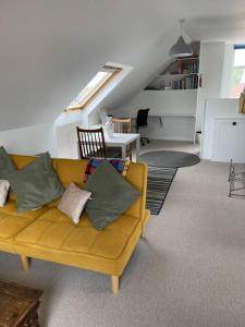 a living room with a yellow couch with pillows at Fantastic sea views. One Bedroom flat near the sea in Selsey