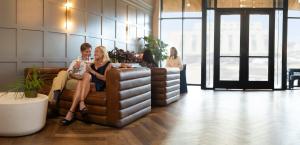 a group of people sitting on a couch in a room at The Thomas Hotel - Premium Square View Suite in Tyler