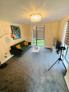 a living room with a green couch and a television at Beautiful and Modern 2 bedroom flat in Colindale in Colindale