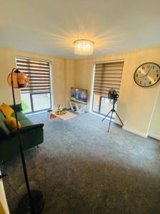a living room with a couch and a clock on the wall at Beautiful and Modern 2 bedroom flat in Colindale in Colindale