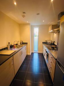 a large kitchen with a black tile floor and counters at Beautiful and Modern 2 bedroom flat in Colindale in Colindale