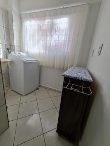 een kleine badkamer met een vuilnisbak en een raam bij Apartamento com mobília nova 101! in Francisco Beltrão