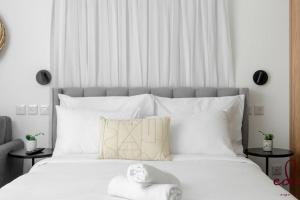 um quarto com uma grande cama branca com almofadas brancas em דירה יפהפייה עם מרפסת 100 מטר מהים - by Edom em Eilat