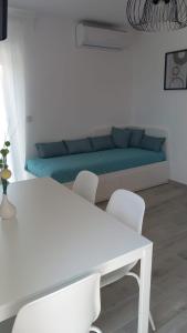 a living room with a white table and a blue couch at Apartmani HERMES Jadrija in Šibenik