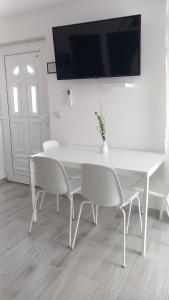 a white table and chairs with a television on a wall at Apartmani HERMES Jadrija in Šibenik