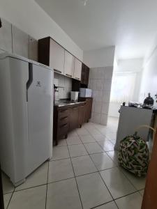 a kitchen with a white refrigerator and a tiled floor at Apartamento com mobília nova 101! in Francisco Beltrão