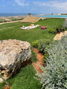 a garden with a large rock next to the water at Villa La Falaise in Oualidia