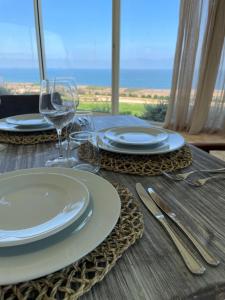 a wooden table with plates and wine glasses on it at Villa La Falaise in Oualidia