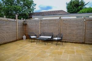 a patio with four chairs and a table in front of a fence at Luxury 5 Star apartments, Parking, Garden, near Metro Stations 10-15mins to London in London