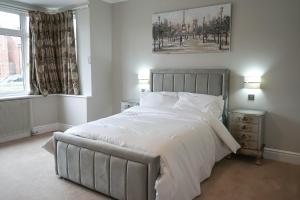 Un dormitorio con una gran cama blanca y una ventana en Luxury 5 Star apartments, Parking, Garden, near Metro Stations 10-15mins to London, en Londres