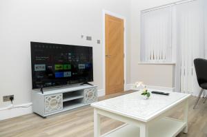 a living room with a television and a white table at Luxury 5 Star apartments, Parking, Garden, near Metro Stations 10-15mins to London in London