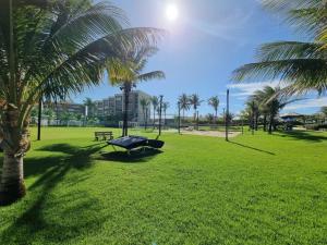 un parc avec des palmiers et un banc dans l'herbe dans l'établissement Porto das dunas - Apt pé na areia ao lado do Beach Park, à Aquiraz