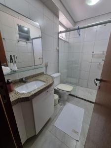 La salle de bains est pourvue d'un lavabo, de toilettes et d'un miroir. dans l'établissement Porto das dunas - Apt pé na areia ao lado do Beach Park, à Aquiraz