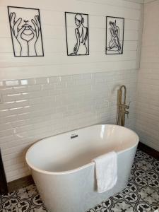 Casita at the Winery في Battle Ground: حوض استحمام أبيض في حمام مع صور على الحائط
