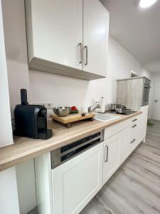 a kitchen with white cabinets and a counter top at Home Inn Apartments - 101 in Bielefeld +3 photos