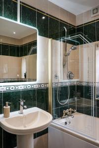 uma casa de banho com um lavatório, um chuveiro e uma banheira em Luxury 5 Star apartments, Parking, Garden, near Metro Stations 10-15mins to London em Londres