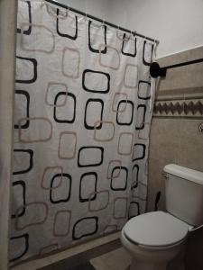 a bathroom with a toilet and a shower curtain at Hostel Casa Xtakay in Valladolid