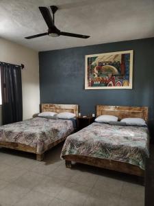 a bedroom with two beds and a ceiling fan at Hostel Casa Xtakay in Valladolid