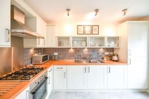 a kitchen with white cabinets and a stove top oven at Fabulous Flat in Stirling