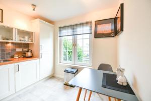 uma cozinha com armários brancos, uma mesa e uma janela em Fabulous Flat em Stirling