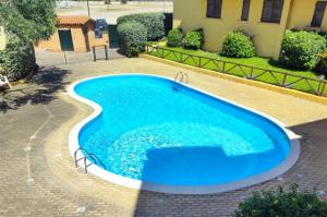 a large swimming pool with blue water in a yard at Kary Studio Apartment in Olbia