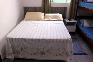 a bedroom with a bed with a white comforter at Pousada Decarli Executiva Aeroporto Florianópolis in Florianópolis