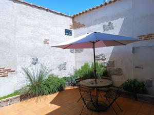 a table and chairs with an umbrella on a patio at Las Gemelas 1 y 2 apartamentos turísticos in Cardeñosa