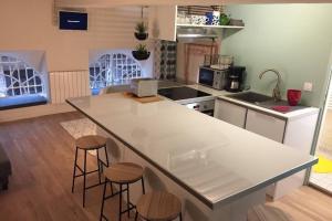 een keuken met een wit aanrecht en krukken bij Appartement cosy de caractère - Place Sathonay in Lyon