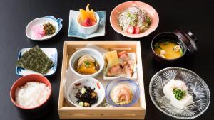 a table topped with bowls of different types of food at Sagayamato Onsen Hotel Amandi in Saga