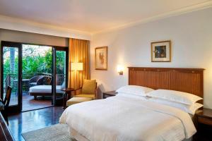 a bedroom with a large bed and a balcony at Sheraton Senggigi Beach Resort in Senggigi
