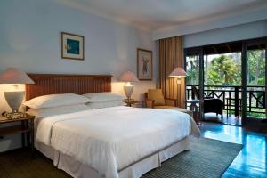 a bedroom with a large white bed and a balcony at Sheraton Senggigi Beach Resort in Senggigi