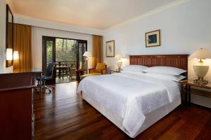 a bedroom with a large white bed and a desk at Sheraton Senggigi Beach Resort in Senggigi