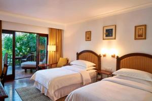 a hotel room with two beds and a balcony at Sheraton Senggigi Beach Resort in Senggigi